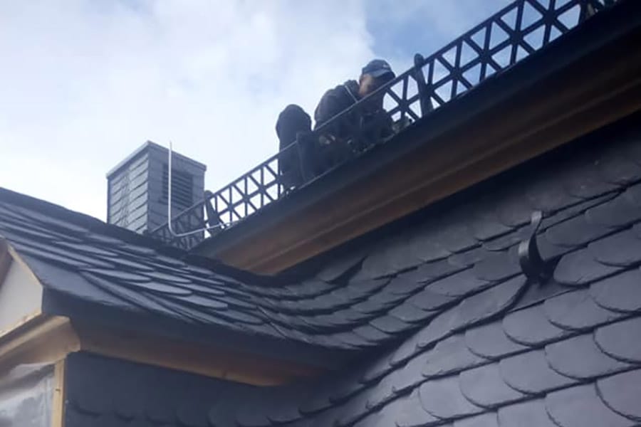 Ein Dachdecker arbeitet auf einem Dach mit Dachhaken.