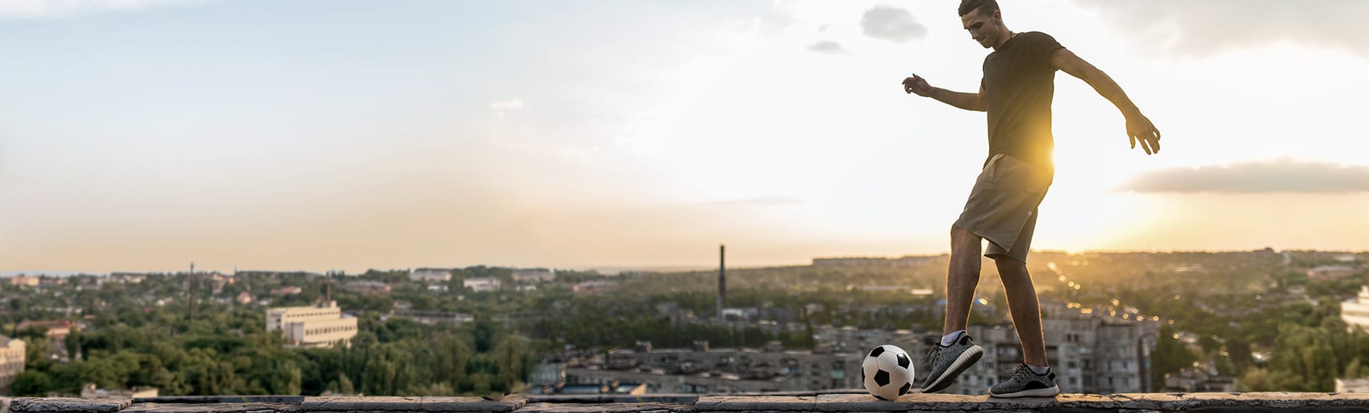 Ein junger Mann spielt Fußball auf einem Flachdach